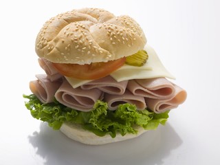 A sesame seed roll with ham, cheese, tomato and gherkins