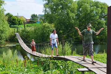 People walk on  suspension bridge over the river
