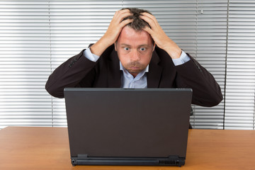 Frustrated middle aged businessman sitting at office desk