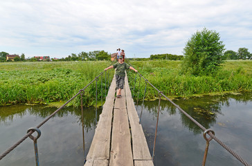 Fototapeta premium People walk on suspension bridge over the river