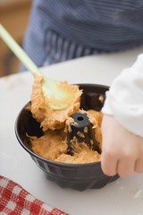 Child putting cake mixture into ring cake tin