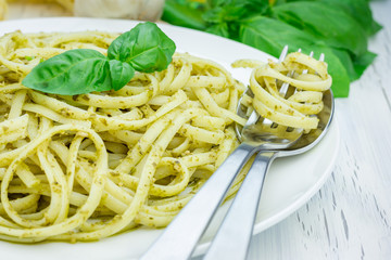 Tagliatelle pasta with pesto sauce on a white plate