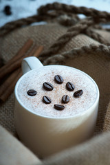 Cappuccino coffee cup,coffee beans, rope and cinnamon on burlap sack
