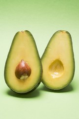 Avocado, halved, against green background