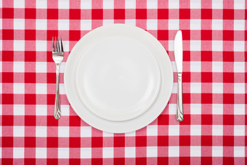 Empty white plates on checkered tablecloth