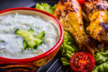Tzatziki sauce. Tzatziki dressing. Tzatziki dressing with grilled chicken legs and fresh vegetable,lettuce leaf and cherry tomatoes. Grilled chicken legs, lettuce and tomatoes. Mediterranean cuisine.