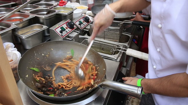 Street cooks prepares Chinese noodles with vegetables.