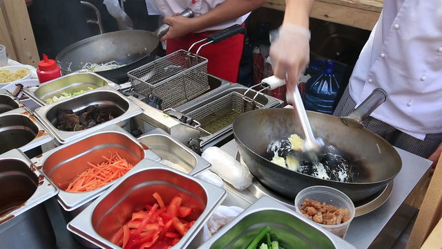 Street cooks prepares Chinese noodles with vegetables.