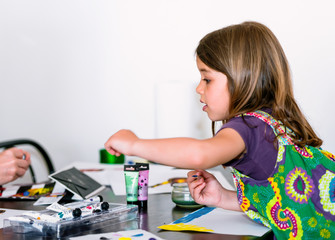 Expressive portrait of a pretty young girl doing paint with her mum
