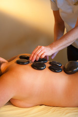 Obraz na płótnie Canvas Adult woman receiving a hot rocks spa treatment on her back.