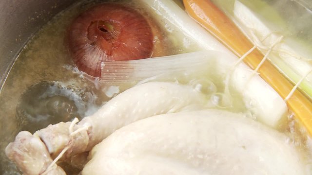 Chicken, onion and mirepoix simmering in a pot