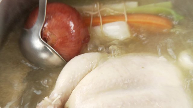 Chicken, onion and mirepoix simmering in a pot