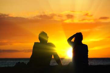 Couple watching the sunset on a beach in Maui Hawaii USA