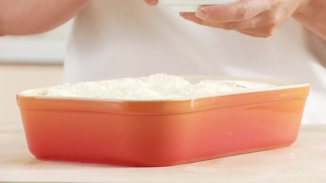 Lasagne being sprinkled with butter flakes