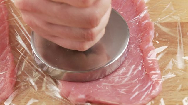 Veal escalopes being tenderised between layers of clingfilm