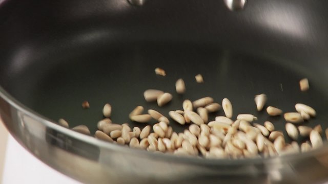 Pine nuts being roasted in a pan