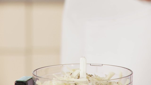 Grated cheese in a mixer being seasoned with pepper