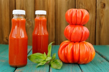 Two bottles of homemade ketchup with fresh green basil and pile