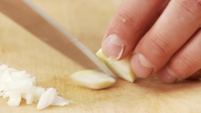 A garlic clove being finely chopped