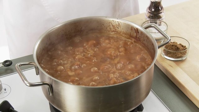 Goulash being seasoned with pepper, salt and ground cumin