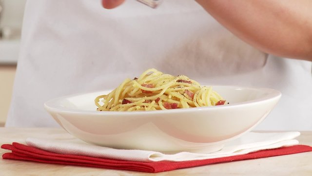 Spaghetti alla Carbonara being sprinkled with pepper