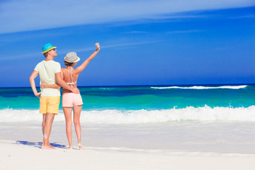 Back view of couple in bright clothes having fun at tropical