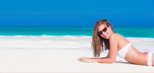 Young woman in white bikini enjoying her day at tropical beach
