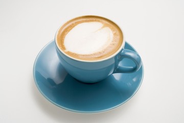 A cappuccino in a blue cup with a milk foam heart