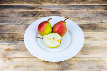Naklejka na ściany i meble Two and half pears in white plate, rustic wooden table