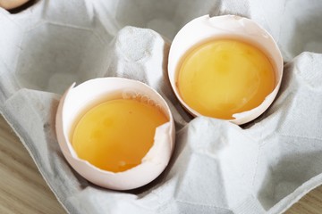 Two broken eggs in their shells in egg box