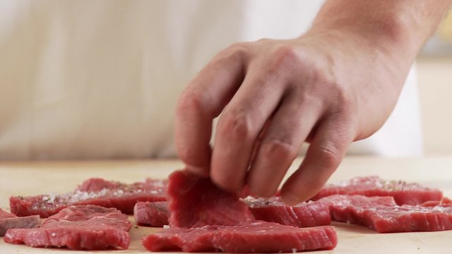 Seasoned veal escalopes being turned