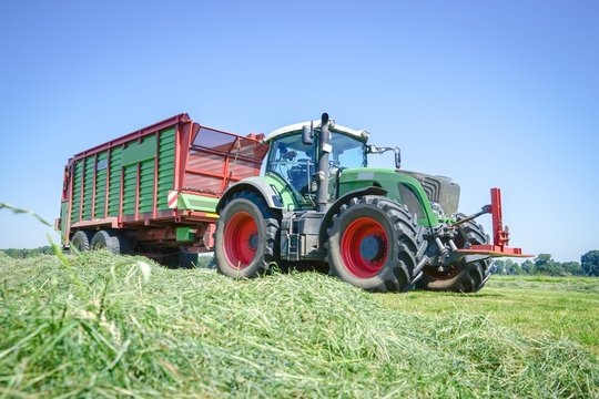 Traktor mit Ladewagen bei der Ernte von Gras f&uuml;r Silage