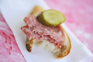 Salami and bread with gherkin, a bite taken