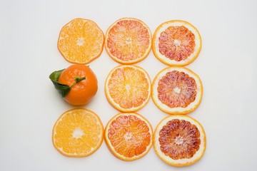 Unpeeled clementine and slices of different oranges from above