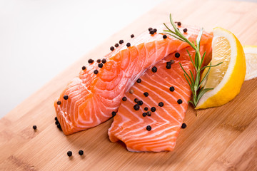Close up on fresh salmon fillet with rosemary, pepper and lemon.