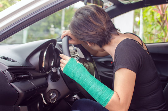 woman with broken hand in cast sitting in car, insurance concept