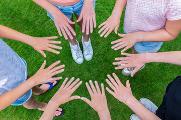 Many children hands joining in circle above grass