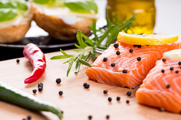 Close up on fresh salmon fillet with rosemary, paprika, pepper and lemon.