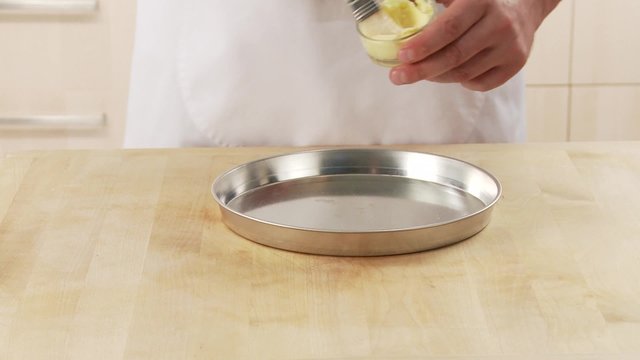 A tart dish being brushed with butter
