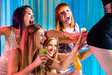 Drunk women with fancy cocktails in strip club