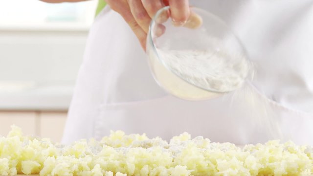 Flour being sprinkled over cooked potatoes