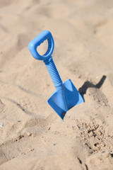 blue beach shovel stuck in the sand by a child