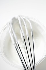 Beaten egg white on whisk and in plastic tub