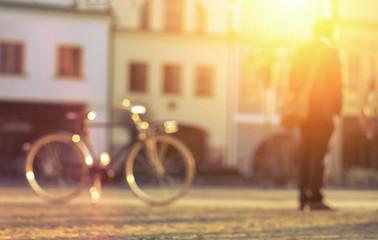 Blurred man with bicicle stay on the street at sunny day.