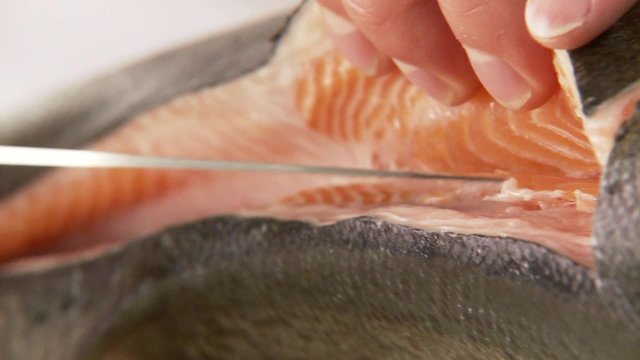 Salmon being filleted - fillet being removed from the spine
