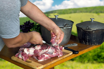 Man cut the meat on wooden table in nature background