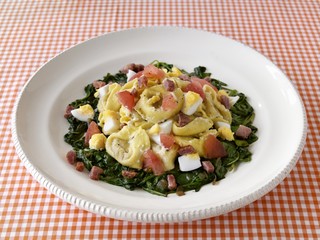 Tortellini with boiled egg and diced bacon on spinach