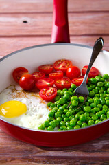 Breakfast with fried egg, green peas and cherry tomatoes