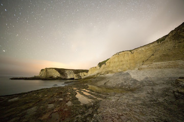 Fototapeta na wymiar Coastal rocks in a dark with star trails