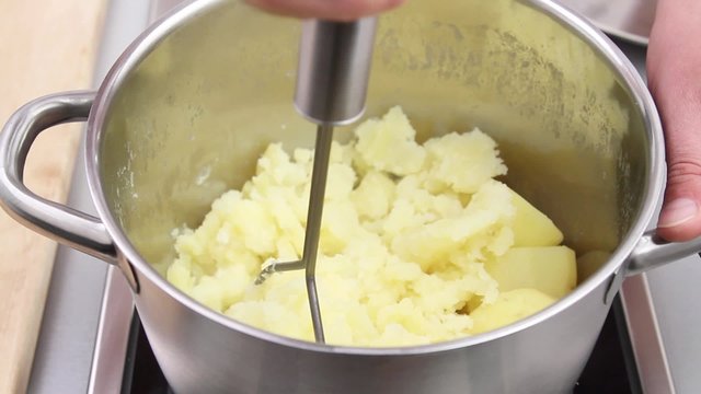 Cooked potatoes being mashed